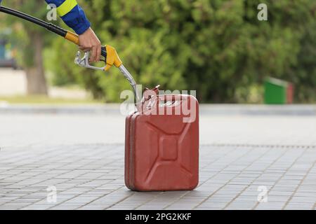 Ein Mann füllt kanister an einer Tankstelle. Ein Mann füllt an einer Tankstelle Benzin in einen Kanister. Ich gieße Benzin in einen Kanister. Stockfoto