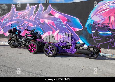 Zwei maßgeschneiderte Fahrräder, die vor einer Wand mit farbenfrohen Graffiti und Straßenkunst geparkt werden Stockfoto