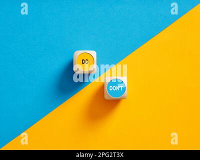 Die Worte "tun" und "nicht tun" auf hölzernen Druckknöpfen. Verhaltensregeln. Stockfoto