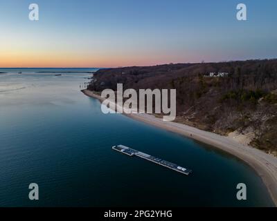 Ein Luftblick auf den Port Jefferson Harbor während eines wunderschönen und wolkenlosen Sonnenuntergangs im Winter Stockfoto