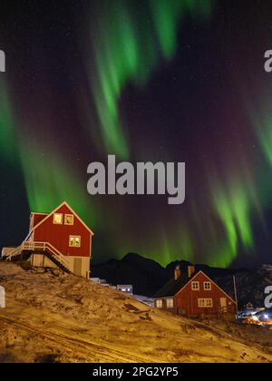 Nordlichter über der Stadt. Stadt Tasiilaq (früher Ammassalik genannt), die größte Stadt in Ostgrönland. Amerika, Grönland, Tasiilaq, dänischer ter Stockfoto