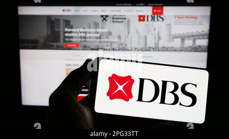 Person, die ein Smartphone mit dem Logo des Finanzunternehmens DBS Bank Limited in Singapur auf dem Bildschirm vor der Website hält. Konzentrieren Sie sich auf das Display des Telefons. Stockfoto