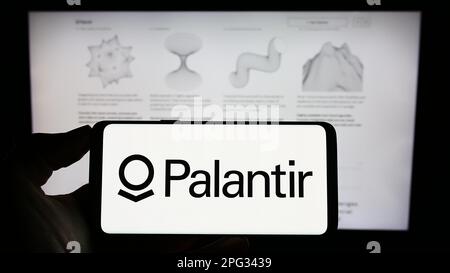 Person, die ein Mobiltelefon mit dem Logo des US-Analyseunternehmens Palantir Technologies Inc. Auf dem Bildschirm vor der Webseite hält. Konzentrieren Sie sich auf das Display des Telefons. Stockfoto
