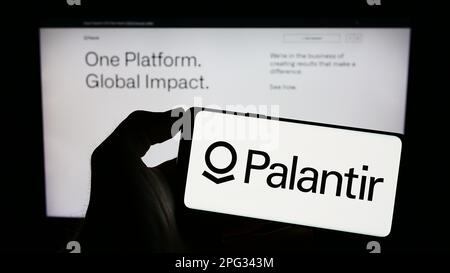 Person, die ein Mobiltelefon mit dem Logo des US-Analyseunternehmens Palantir Technologies Inc. Auf dem Bildschirm vor der Webseite hält. Konzentrieren Sie sich auf das Display des Telefons. Stockfoto