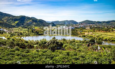 Ein Blick vom Me Linh Coffee Garden über Kaffeebäume, Dap Cam Ly Lake und ein Tal im zentralen Hochland nahe Dalat in Vietnam. Stockfoto