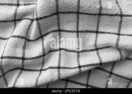 Klassisches Küchenhandtuch mit Karomuster in Schwarz und Weiß. Zerknitterter Textilhintergrund mit sichtbarem Gewebe- und Fadendetail. Ideal für Web- und Druckanwendungen Stockfoto
