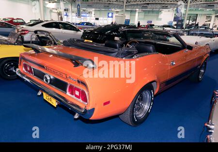 Dreiviertel Rückansicht eines 1973 in Orange und Schwarz, Ford Mustang V8 Cabriolet, Teil der London Classic Car Auction 2023 bei Olympia, London Stockfoto