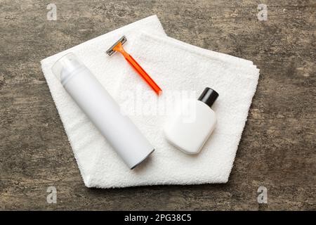 Rasierer-Set. Schermaschine, Handtuch, Lotion und Rasierschaum auf farbigem Hintergrund. Herren Bad Accessoires Draufsicht. Stockfoto
