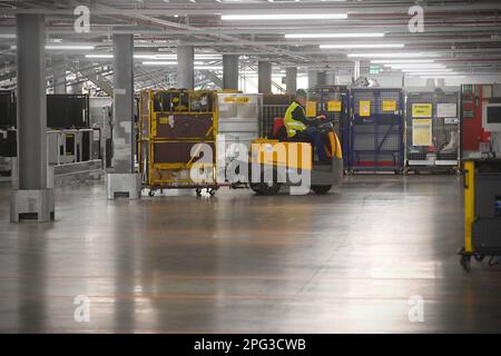 Deutsche Post DHL nahm am 20. März 2023 den größten Paketstandort Deutschlands in Betrieb. Bearbeitung von bis zu 72.000 Paketen pro Stunde im Aschheim II-Paketzentrum bei München. Arbeiter transportiert ein Auto. ? Stockfoto