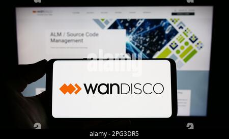 Person, die ein Mobiltelefon mit dem Logo des Softwareunternehmens WANdisco plc auf dem Bildschirm vor der Unternehmenswebseite hält. Konzentrieren Sie sich auf das Display des Telefons. Stockfoto