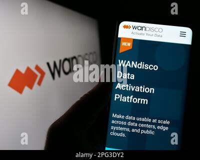 Person, die ein Smartphone mit der Webseite des Softwareunternehmens WANdisco plc auf dem Bildschirm vor dem Unternehmenslogo hält. Konzentrieren Sie sich auf die Mitte des Telefondisplays. Stockfoto