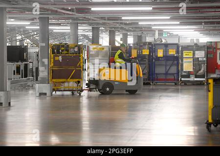 Deutsche Post DHL nimmt am 20. März 2023 den größten Paketstandort Deutschlands in Betrieb. Bearbeitung von bis zu 72.000 Paketen pro Stunde im Aschheim II-Paketzentrum bei München. Arbeiter transportiert ein Auto. ? Stockfoto