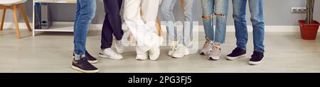 Gruppe junger Menschen in Freizeitkleidung und Turnschuhen, die im Klassenzimmer in Reihe stehen Stockfoto