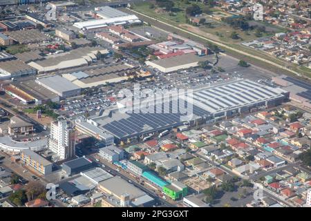 Luftaufnahme eines städtischen Mix-Use-Gebietes mit einem großen Einkaufszentrum mit Solarpaneelen auf dem Dach, ein angrenzender Wohnbereich und Bürogebäude Stockfoto
