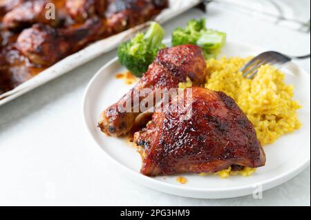 Glasiertes Huhn mit Pilaureis und Brokkoli auf einem Teller Stockfoto