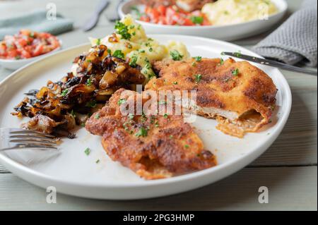 Schweineschnitzel mit gebratenen Zwiebeln und Kartoffelpüree auf einem Teller Stockfoto