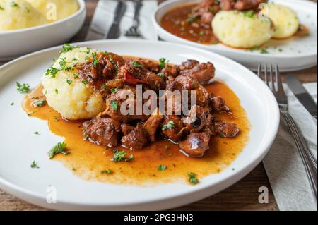 Fleischgericht mit Kartoffelknödeln auf einem Teller Stockfoto