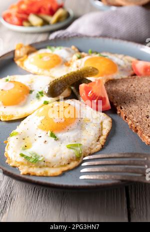 Spiegeleier mit sonniger Seite nach oben mit Gurken, Tomaten und Brot Stockfoto