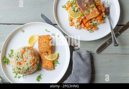 Gebratener Lachs mit braunem Reis und Gemüse auf einem Teller Stockfoto