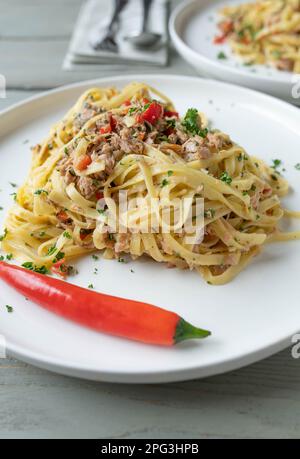 Pasta mit Thunfisch, Knoblauch, Chili, Olivenöl und Petersilie. Traditionelle italienische Küche, Noodles aglio e olio auf dem Teller Stockfoto