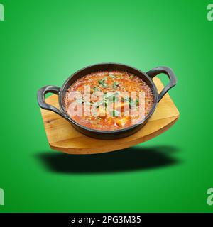 Schwimmendes Matarpaneel in einer kleinen Pfanne auf grünem verlaufendem Hintergrund gebacken Stockfoto