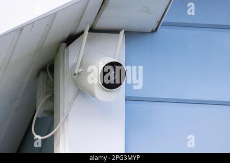 Eine Außenkamera mit Bewegungsmelder und WLAN-Antennen ist an einer Ecke des ländlichen Holzhauses montiert Stockfoto