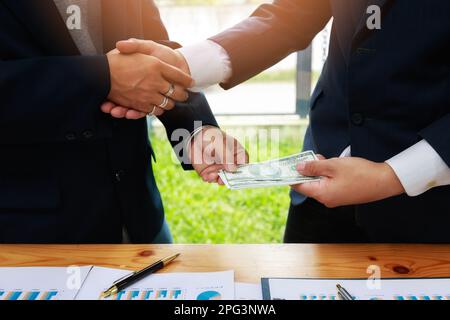 Geschäftsmann-Handschlag und Dollarscheine in den Händen. Unehrliches Betrügen im Geschäft illegales Geld, Bestechung und Korruption Konzept. Bankkunden kommen Stockfoto