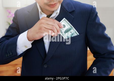Nahaufnahme eines jungen Mannes in formeller Kleidung, der Geld in seine Tasche steckt. Ein Geschäftsmann holt die Banknote aus der Anzugtasche. Stockfoto