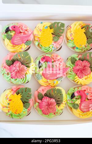 Geschenkbox mit bunten Flamingo-Cupcakes, Obst und Blumen für eine tropische Geburtstagsparty Stockfoto