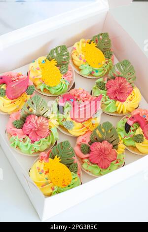 Geschenkbox mit bunten Flamingo-Cupcakes, Obst und Blumen für eine tropische Geburtstagsparty Stockfoto