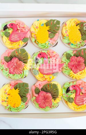 Geschenkbox mit bunten Flamingo-Cupcakes, Obst und Blumen für eine tropische Geburtstagsparty Stockfoto