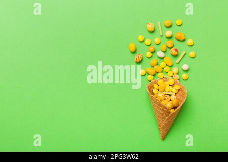 Waffelkonus voller traditioneller Süßigkeiten, die auf farbigen Hintergrund fallen, mit Platz für Kopien. Frohes Weihnachtsangebot. Stockfoto