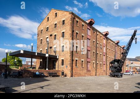 Ein alter Bahndampfkran steht vor einem umgebauten Lagerbürogebäude am regenerierten Kai von Gloucester Docks. Stockfoto