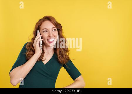 Glückliche rothaarige Frau, die mit dem Handy spricht Stockfoto