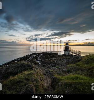 Die Sonne geht über dem Battery Point Lighthouse in Portishead am Bristol Channel unter, mit den Hügeln von Südwales dahinter. Stockfoto