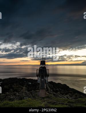 Die Sonne geht über dem Battery Point Lighthouse in Portishead am Bristol Channel unter, mit den Hügeln von Südwales dahinter. Stockfoto