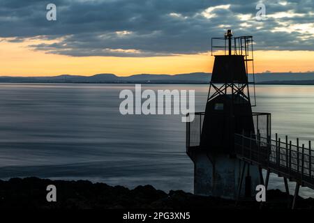 Die Sonne geht über dem Battery Point Lighthouse in Portishead am Bristol Channel unter, mit den Hügeln von Südwales dahinter. Stockfoto