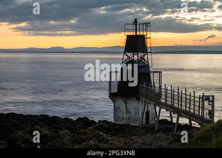 Die Sonne geht über dem Battery Point Lighthouse in Portishead am Bristol Channel unter, mit den Hügeln von Südwales dahinter. Stockfoto