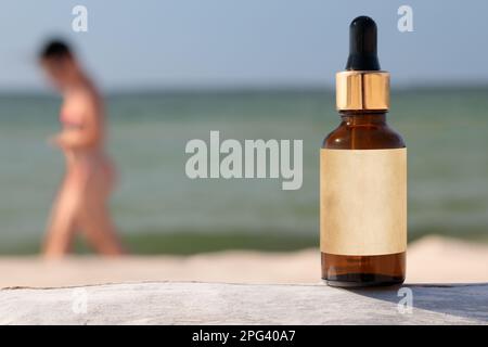 Bernsteinfarbene Glasflasche mit Tropfer in der Nähe von blauem Wasser in der Sonne. Gesichts- und Körperbehandlungskonzept-Banner. M Stockfoto