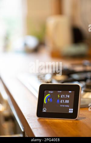 Intelligentes Energiemessgerät für Haushalte auf einer Küchenarbeitsplatte, das die verbrauchte Energiemenge in Pfund Sterling anzeigt Stockfoto