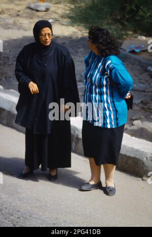 Luxor Egypt Two Women Having a Conversation in the Street - Western und Traditional Dress Stockfoto