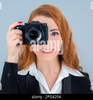 Junge Rothaarige mit einer Kamera. Sie trägt einen Anzug. Stockfoto