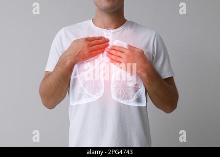 Mann, der Hände nahe der Brust hält, mit Darstellung der Lungen auf grauem Hintergrund, Nahaufnahme Stockfoto