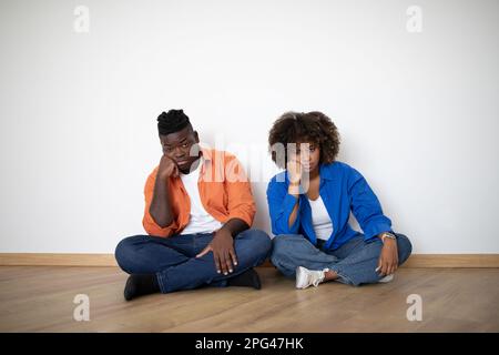 Porträt Eines Gelangweilten Jungen Schwarzen Ehepaars, Das Auf Dem Boden Sitzt, Während Er Nach Hause Zieht Stockfoto