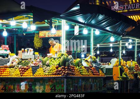 Marrakesch, Marokko - 1. Januar 2020: Unbekannter einheimischer Mann, der abends an der Straßenmarktsaftbar frischen Fruchtsaft verkauft - jede Menge Obst Stockfoto