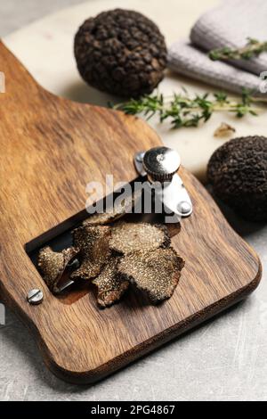 Frische schwarze Trüffel und Schneidemaschine auf grauem Tisch, Nahaufnahme Stockfoto