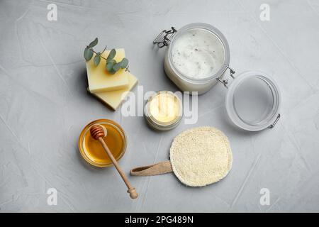 Flache Laienzusammensetzung mit Bienenwachs und kosmetischen Mitteln auf einem Tisch aus hellgrauem Stein Stockfoto