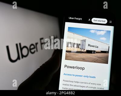 Person, die ein Mobiltelefon mit einer Webseite des amerikanischen Logistikunternehmens Uber Freight auf dem Bildschirm vor dem Logo hält. Konzentrieren Sie sich auf die Mitte des Telefondisplays. Stockfoto