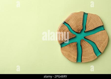 Stilvolle Untersetzer mit Holzbecher auf hellgrünem Hintergrund, Draufsicht. Platz für Text Stockfoto