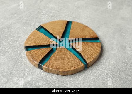 Stilvolle Untersetzer mit Holztasse auf hellgrauem Tisch Stockfoto